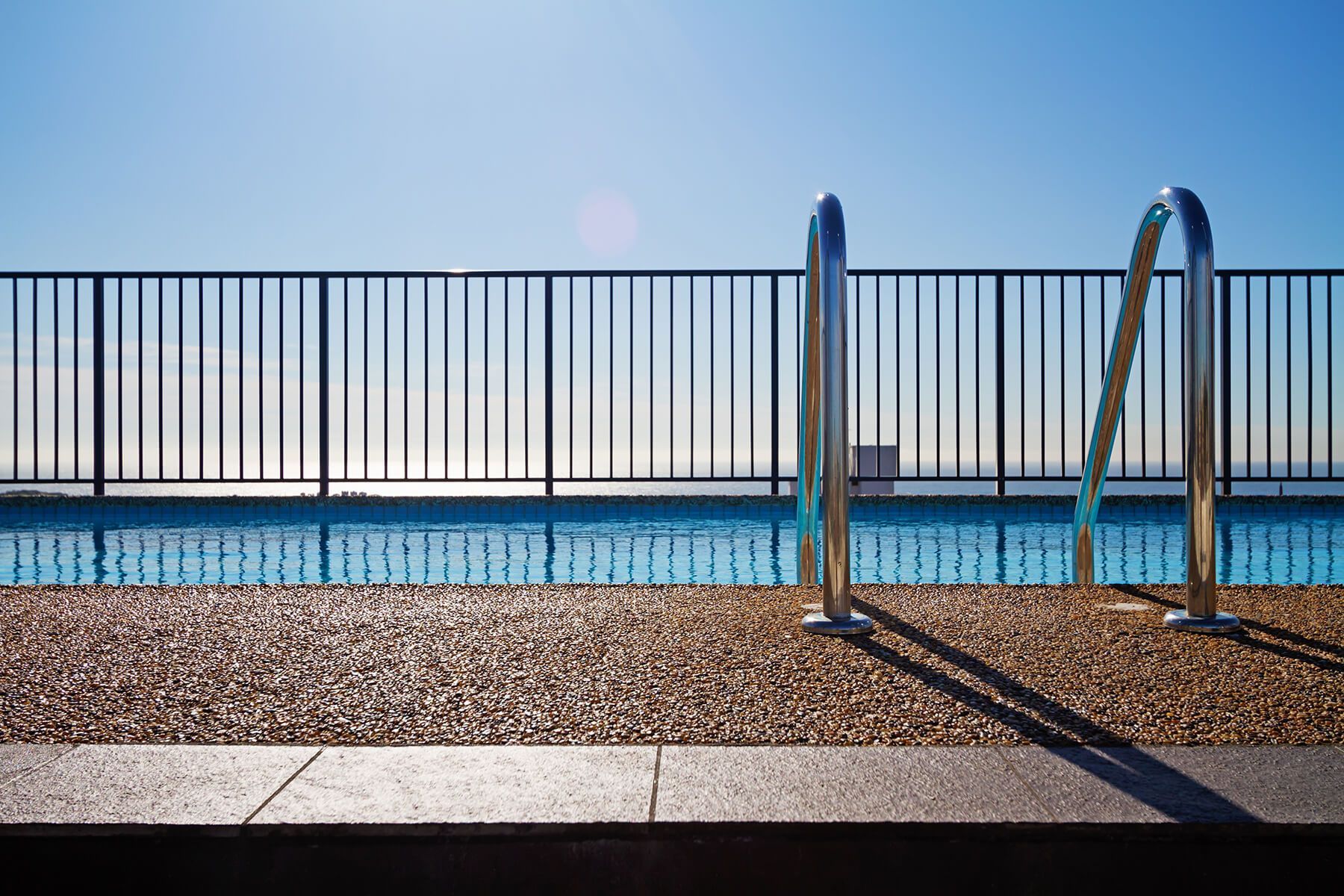 A swimming pool with stairs leading to it and a fence around it.