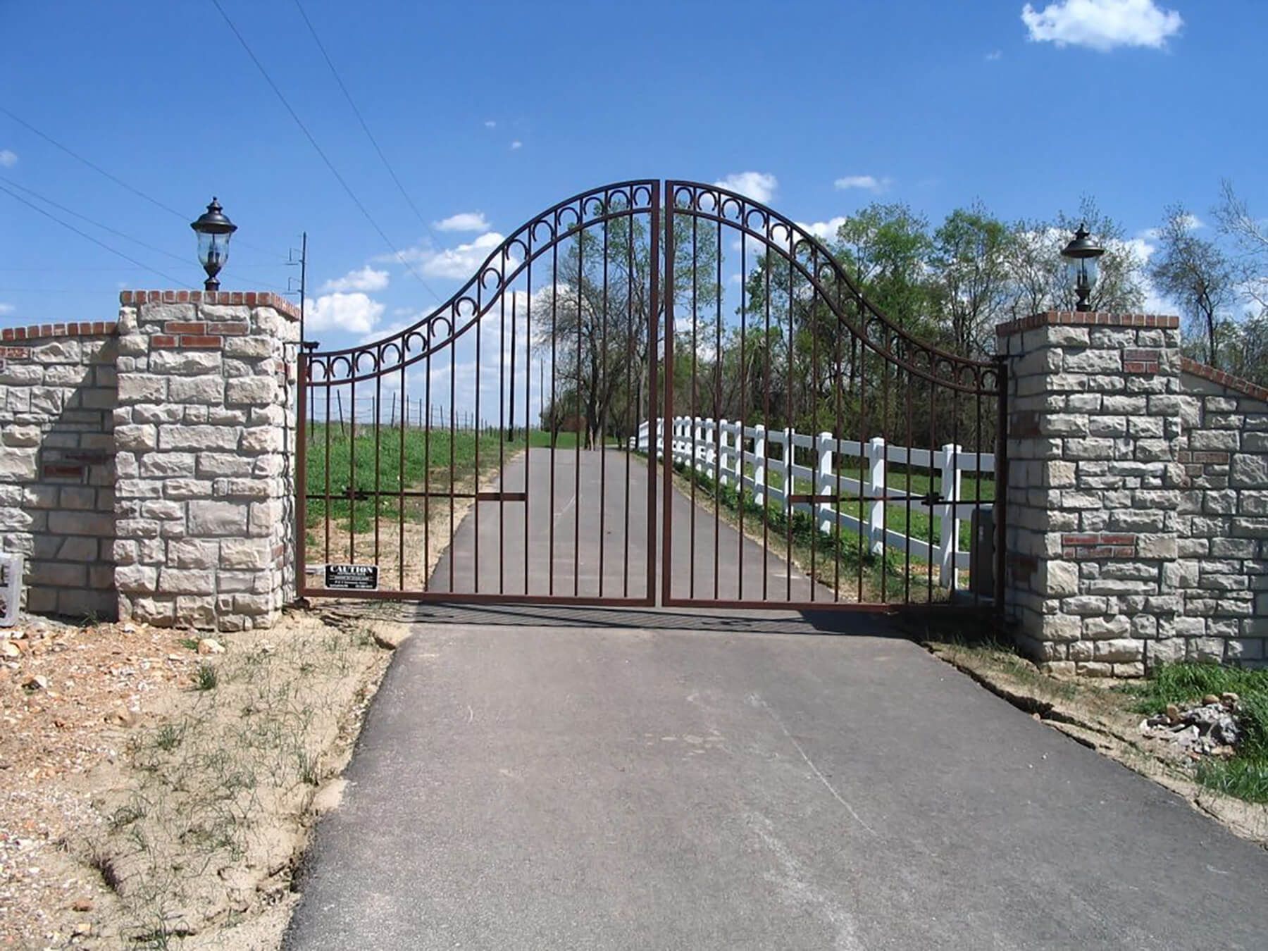 A wrought iron gate with a brick wall behind it | Iron fencing by best Springfield, MO fencing company