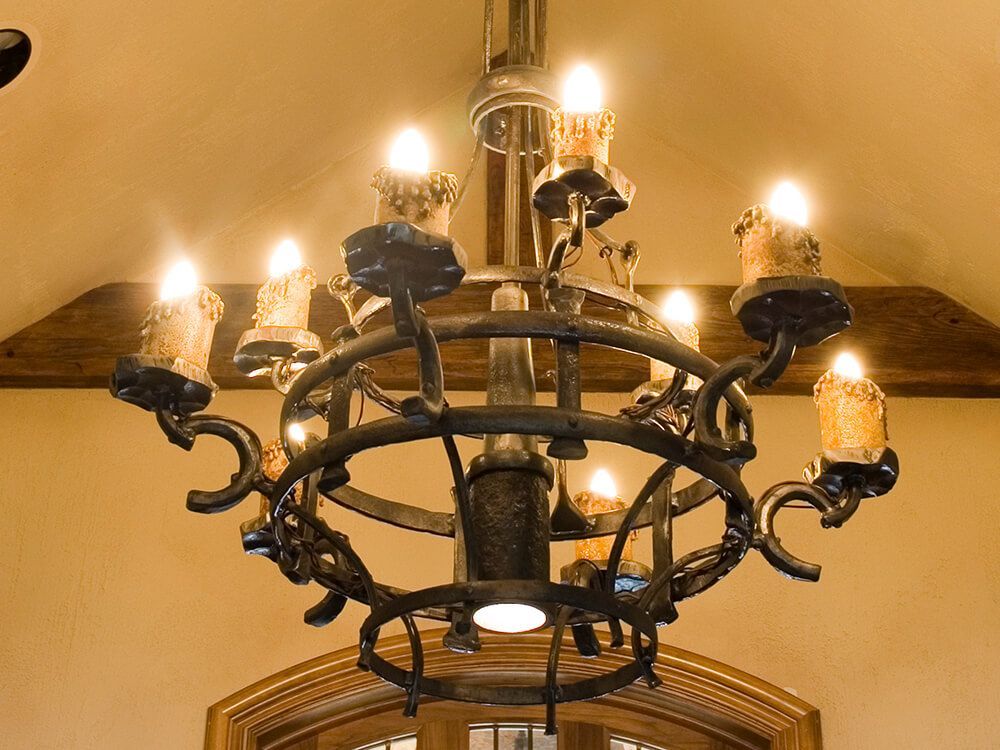 A wrought iron chandelier with candles hanging from the ceiling