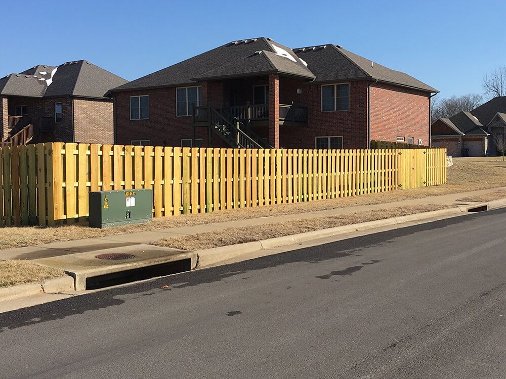 A brick house with a wooden fence in front of it | Fencing company springfield mo