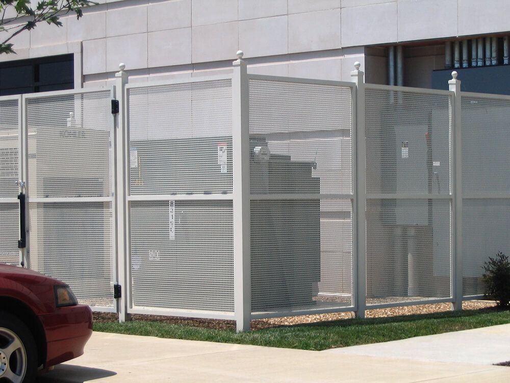 A red car is parked in front of a white fence