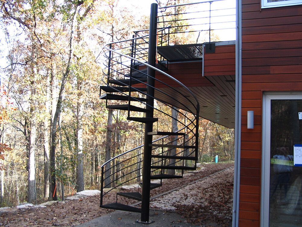 A spiral staircase in front of a wooden house