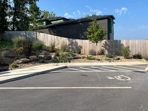 A handicapped parking spot in a parking lot with a wooden fence in the background.