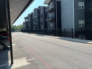 A parking lot next to a building with cars parked in front of it.