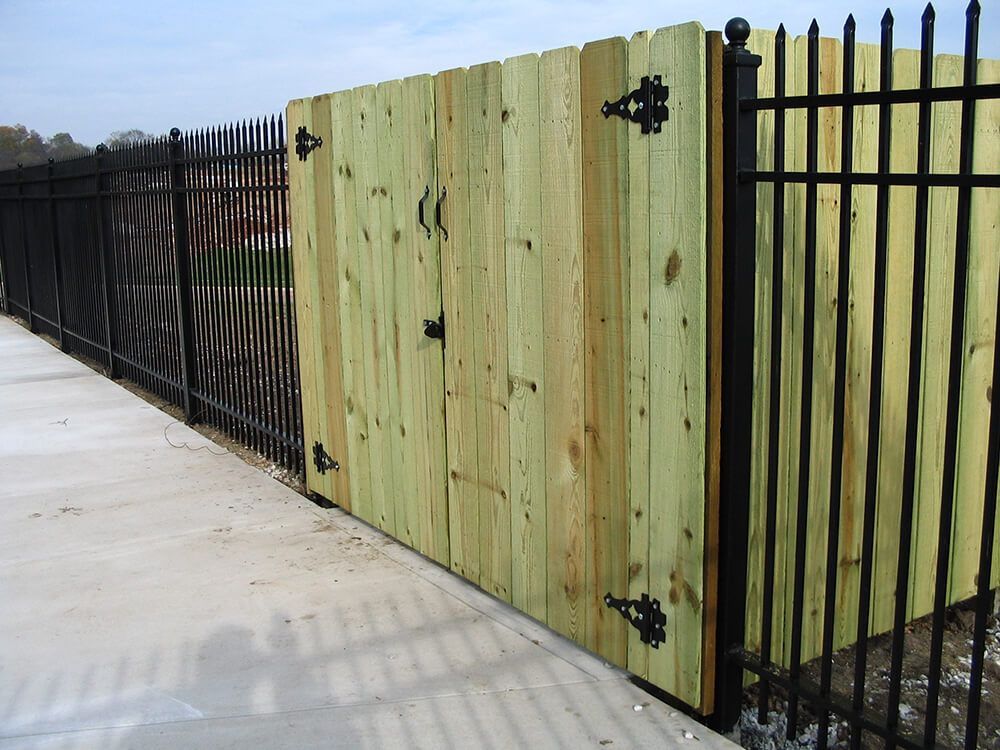 A wooden fence with a black metal fence behind it