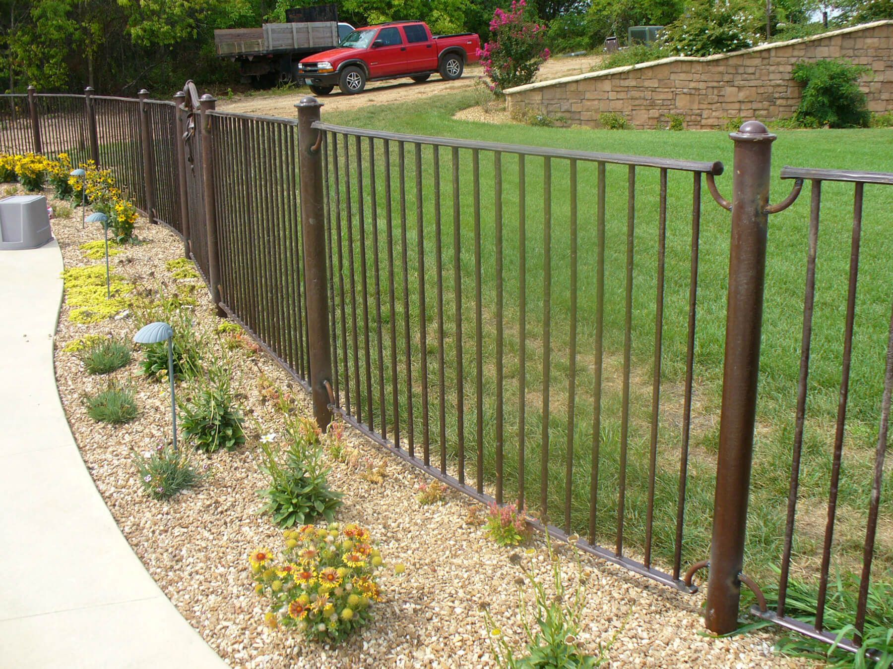 A red truck is parked behind a wrought iron fence