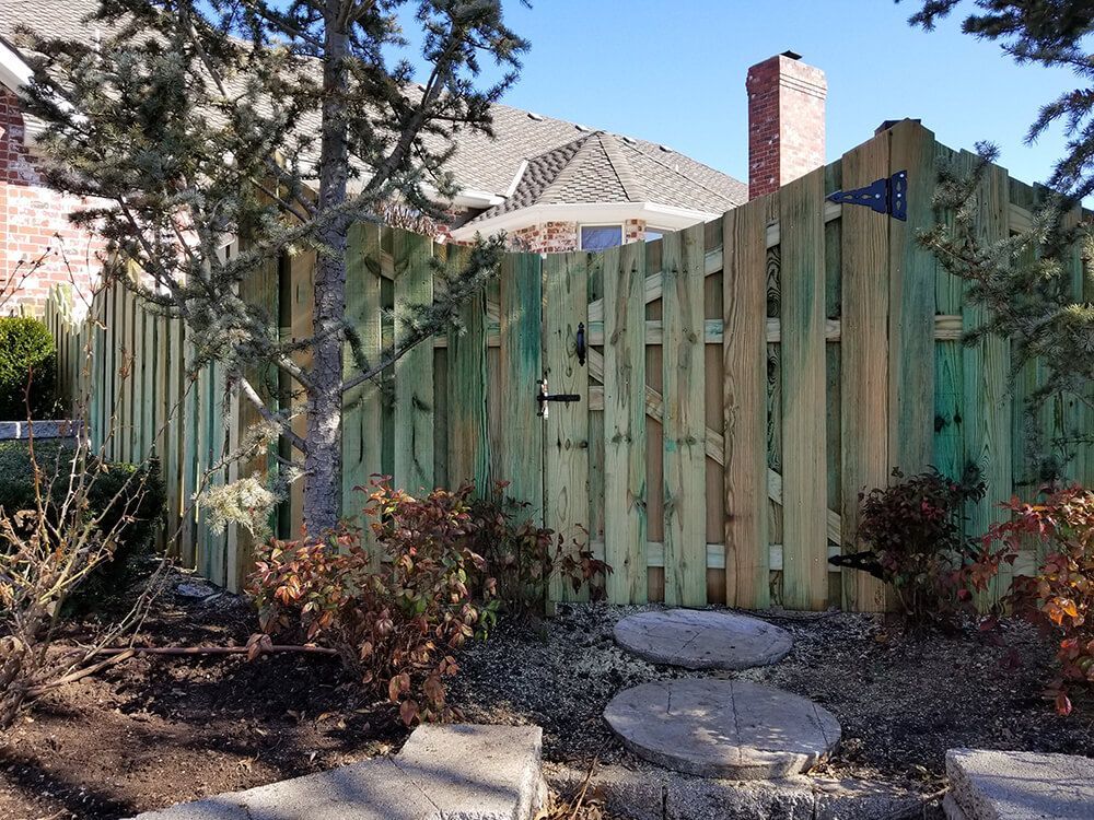 A wooden fence is in the backyard of a house.