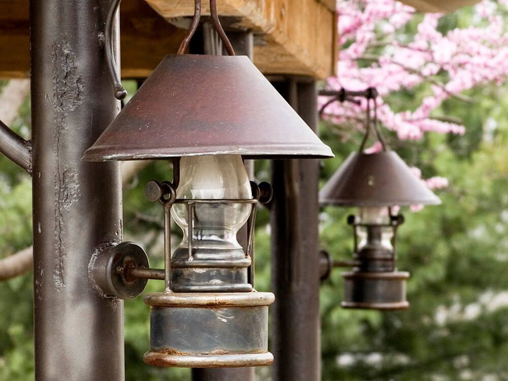 A row of lanterns hanging from a pole with pink flowers in the background