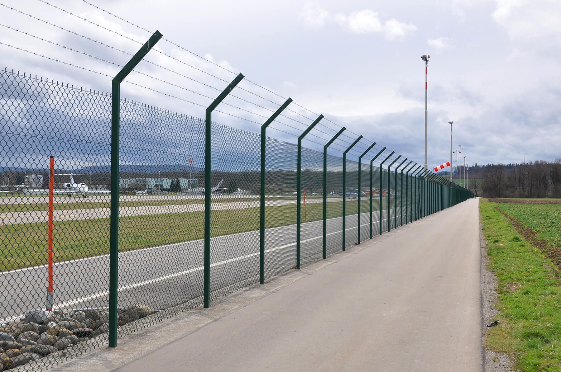 A fence with barbed wire along the side of a road