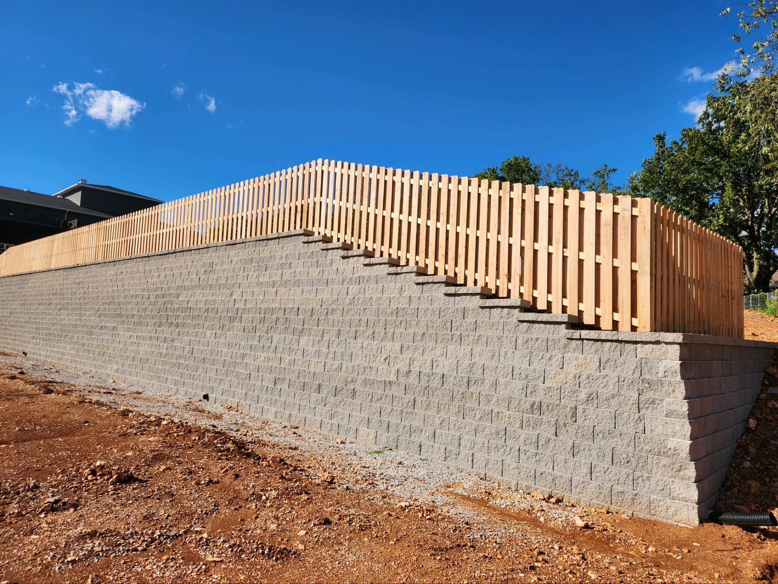 A wooden fence is sitting on top of a brick wall.