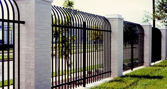 A black metal fence is surrounded by white brick pillars | Commercial Iron fencing Springfield, Branson MO