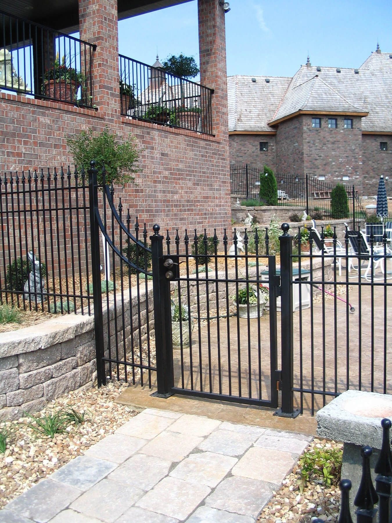 A black fence with a gate in front of a brick building | Installed by fencing company Springfield, Branson, Ozark MO