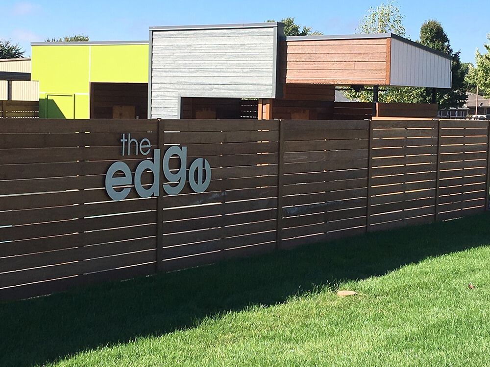 A wooden fence with the words the edge written on it | Commercial fencing springfield mo