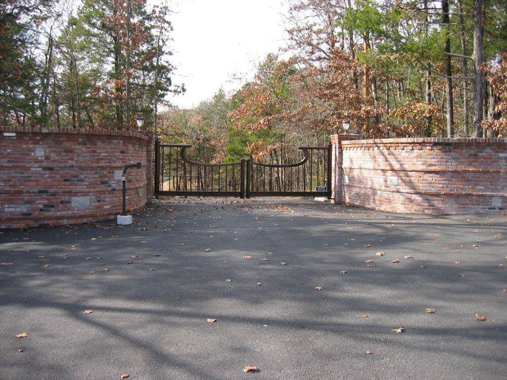 A driveway with a brick wall and a metal gate
