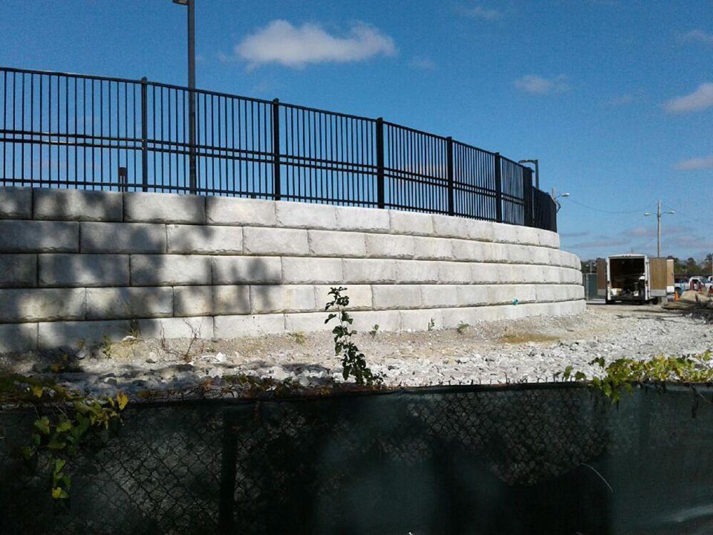 A large concrete wall with a metal fence around it