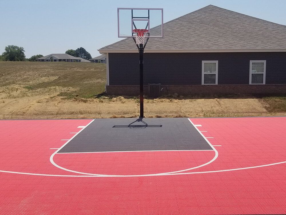 A basketball court with a hoop in front of a house