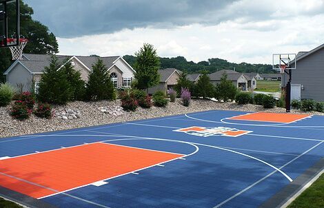 A blue and orange basketball court in a residential area