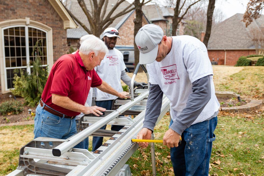 Three workers aligning a metal ladder on a suburban lawn near a house