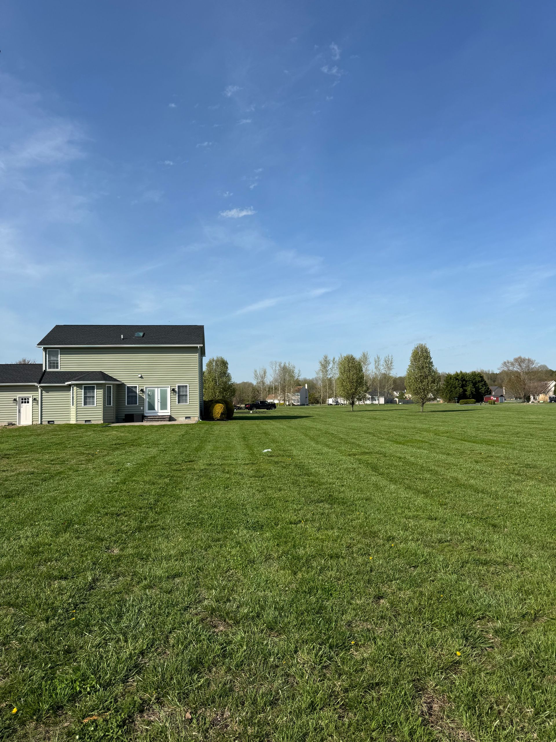 Person installing a sprinkler in a grassy yard beside a brick patio