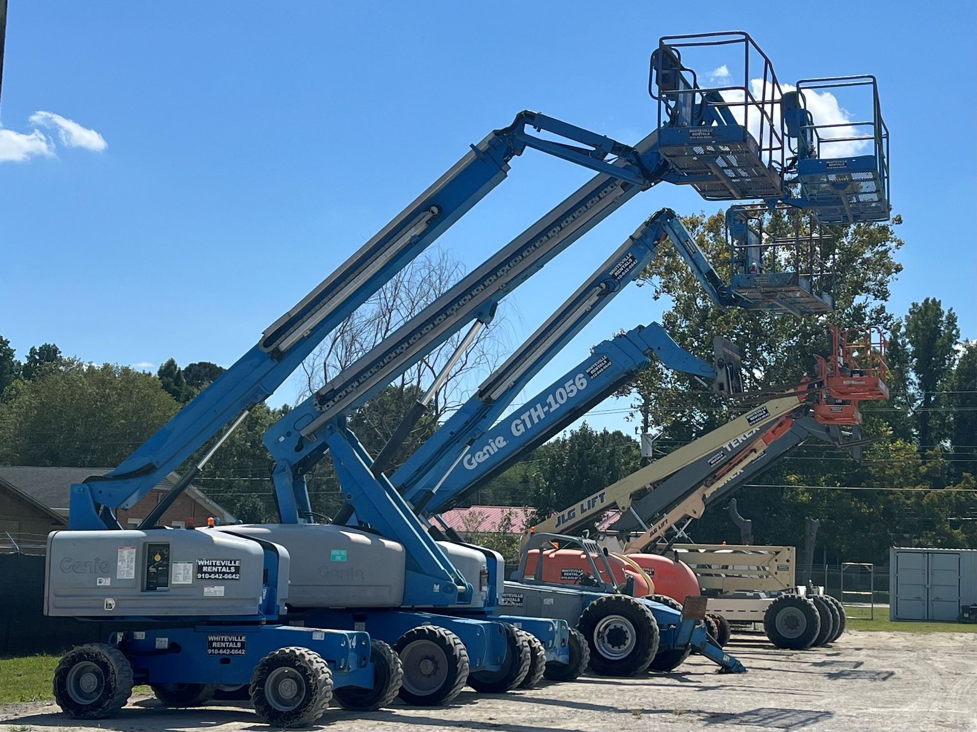 Blue aerial lifts parked outside on a sunny day.
