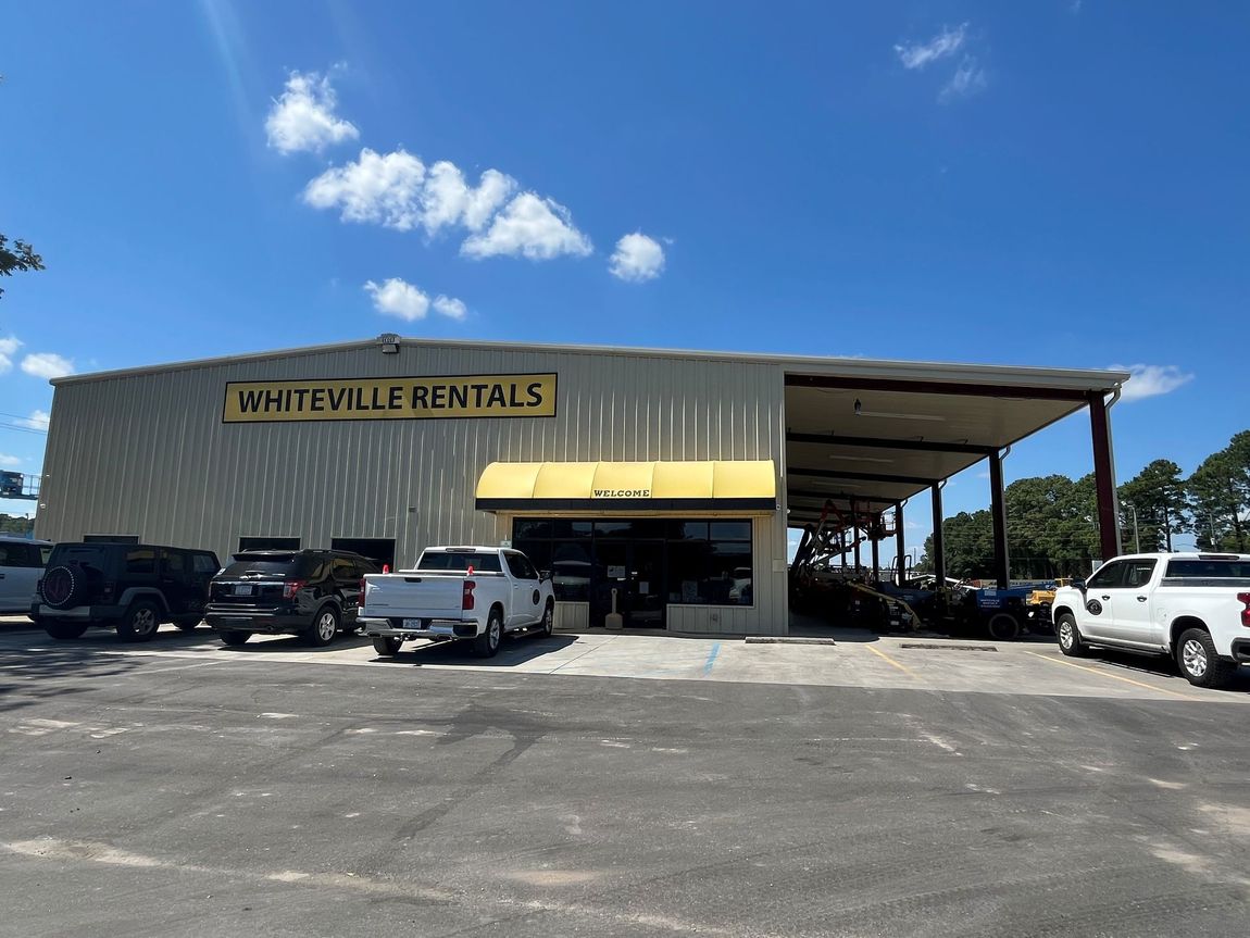 Whiteville Rentals storefront with vehicles parked outside under a blue sky.