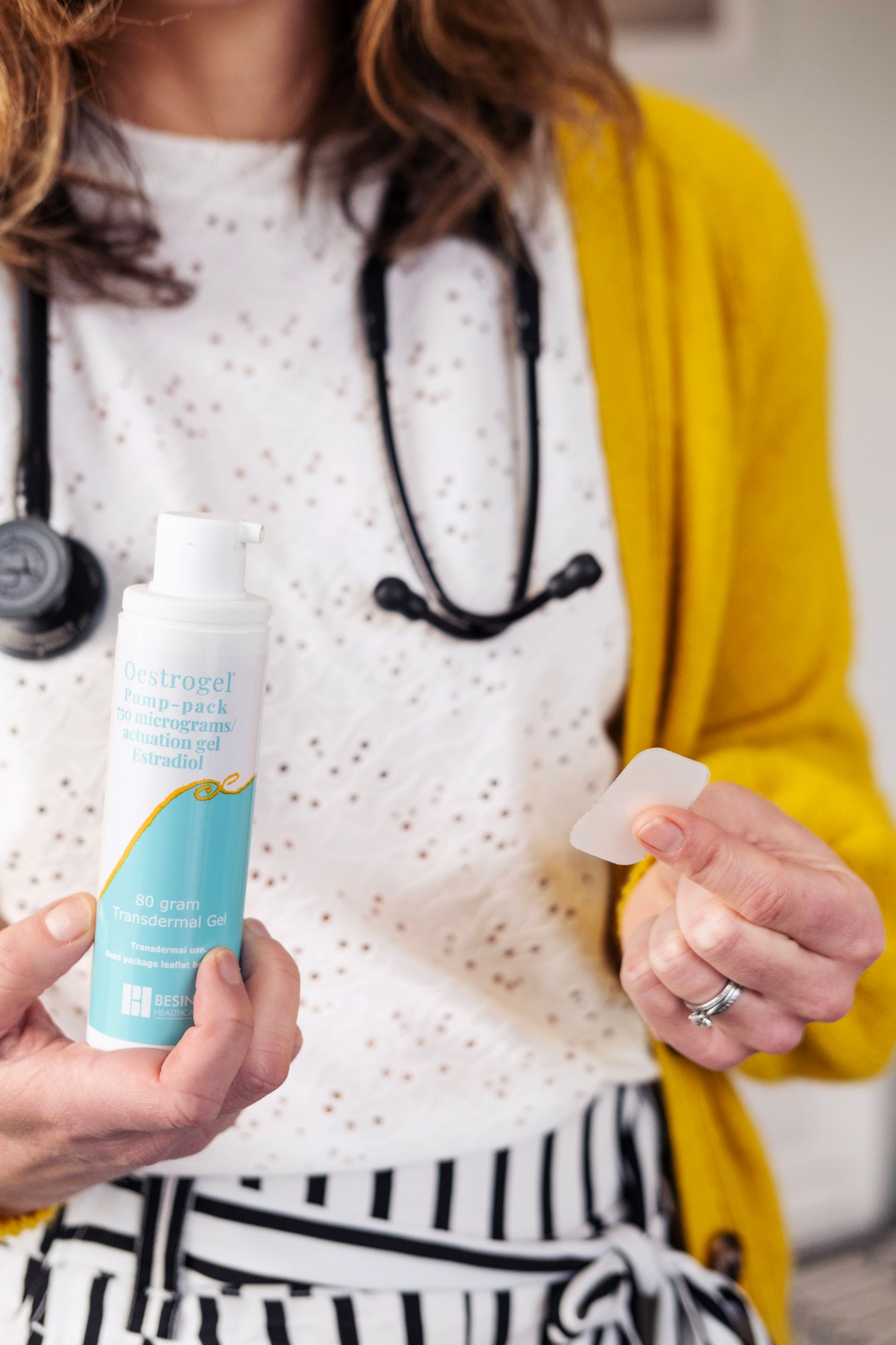 Dr Samantha holding a bottle of liquid and a white object; wearing a yellow sweater and stethoscope.