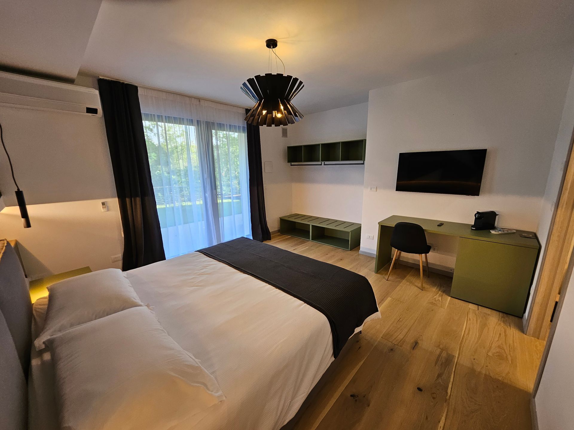 Camera da letto moderna con due letti singoli, TV a parete, scrivania e porte finestre che danno sul balcone.