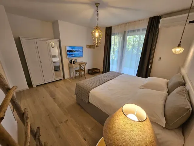 Camera da letto moderna con letto, armadio, scrivania e ampia finestra con tende che si affaccia sul verde.