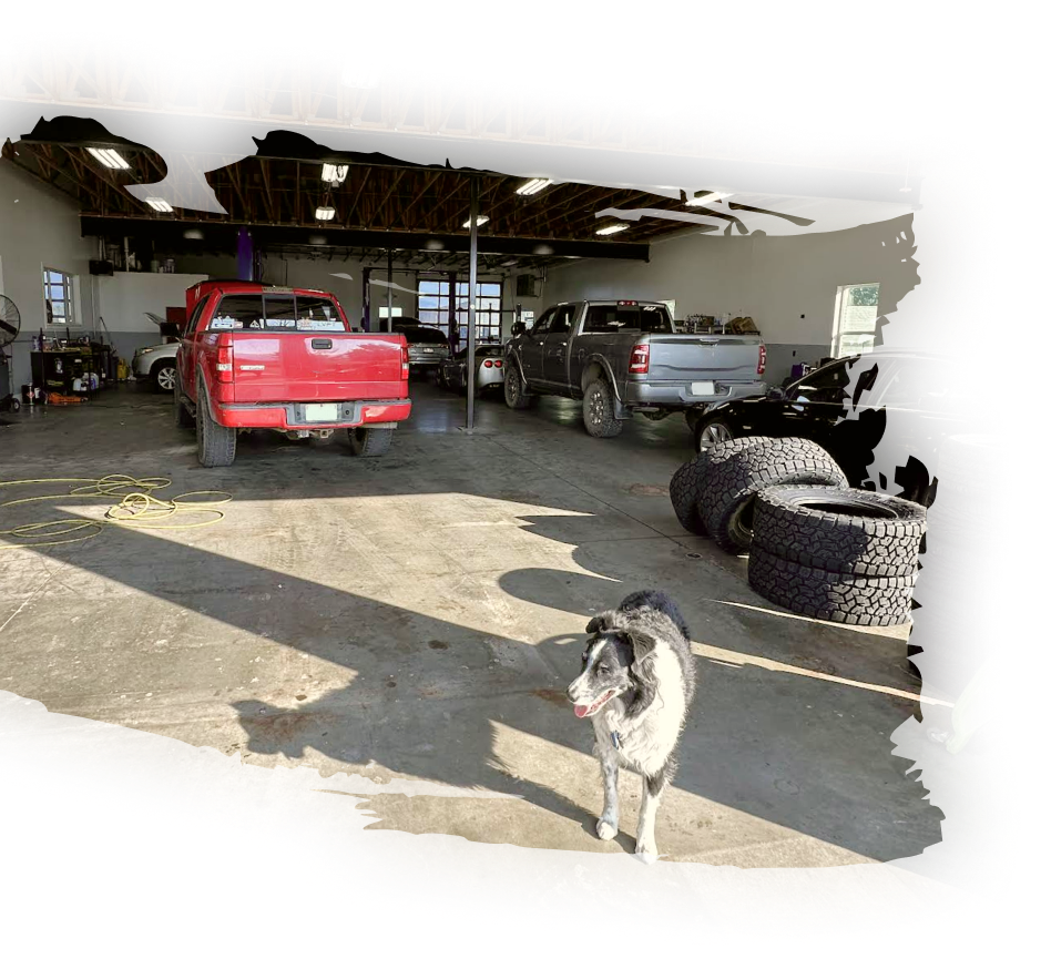 A red truck is parked in a garage next to a dog | Eden Automotive Repair