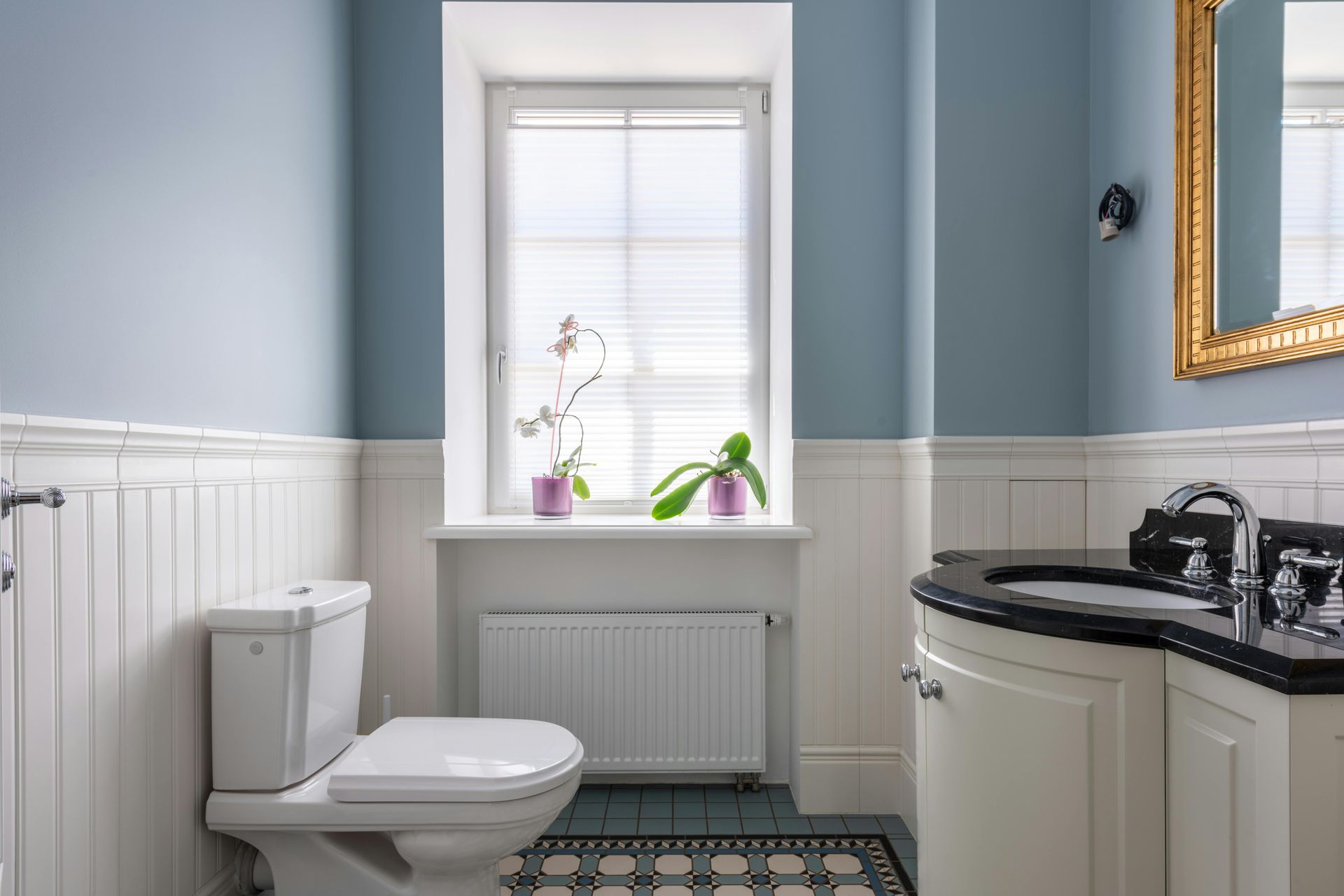 A bathroom with a toilet , sink , mirror and window.