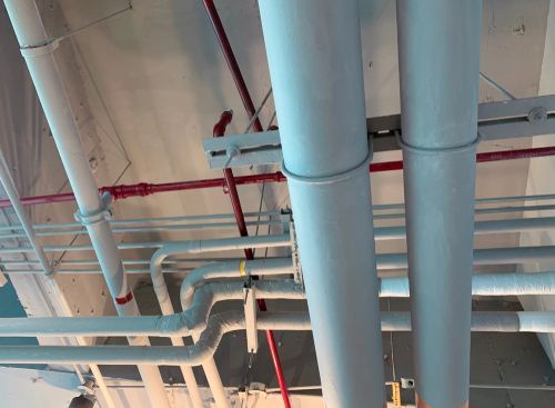 A bunch of pipes are hanging from the ceiling of a building.