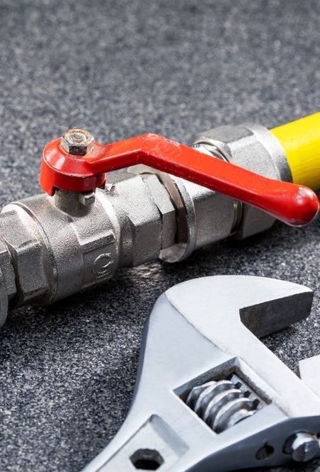A wrench is sitting next to a valve on a table.