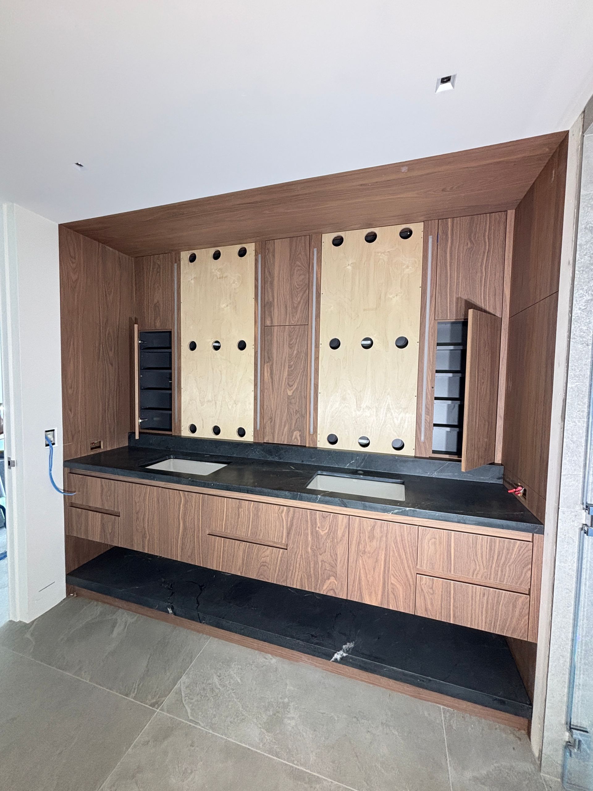 Built-in wooden storage wall with shelves, cabinets, and a long bench in a modern room