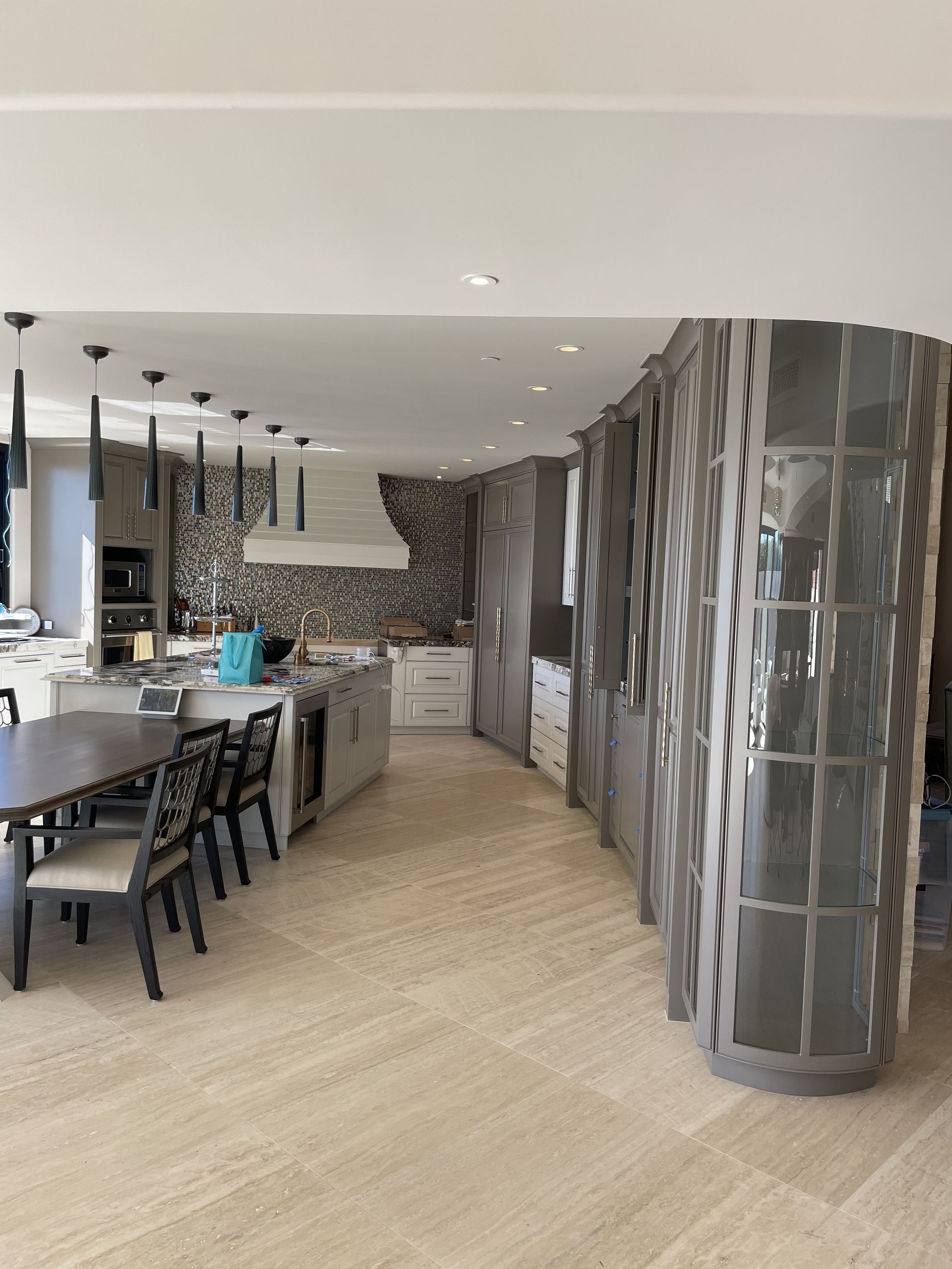 Modern open kitchen and dining area with gray tile accents and pendant lights