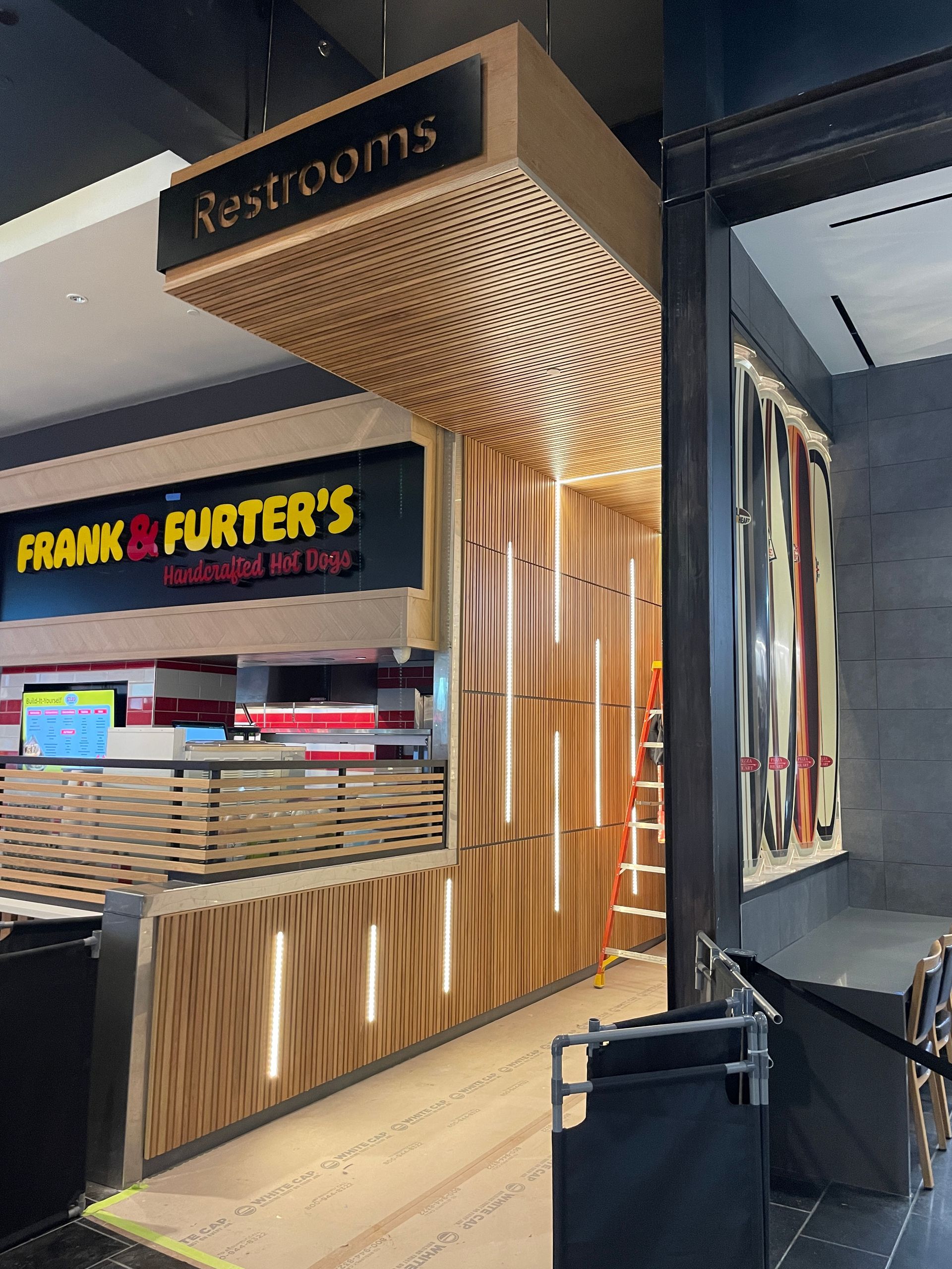 Restaurant entrance with curved wood slats and Frank & Furter's sign in a mall corridor