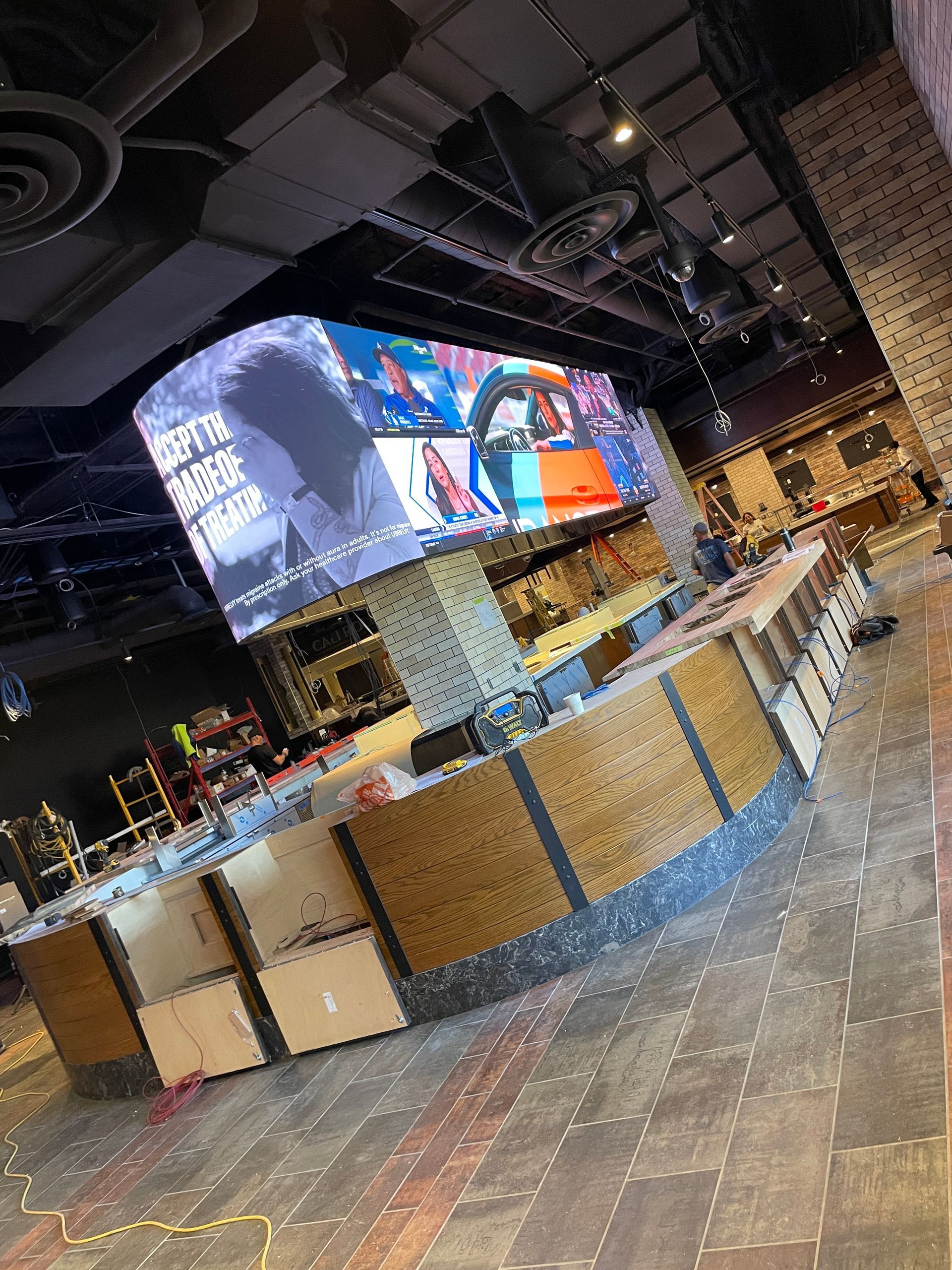 Modern restaurant bar interior with large digital menu screens and rows of tables and chairs