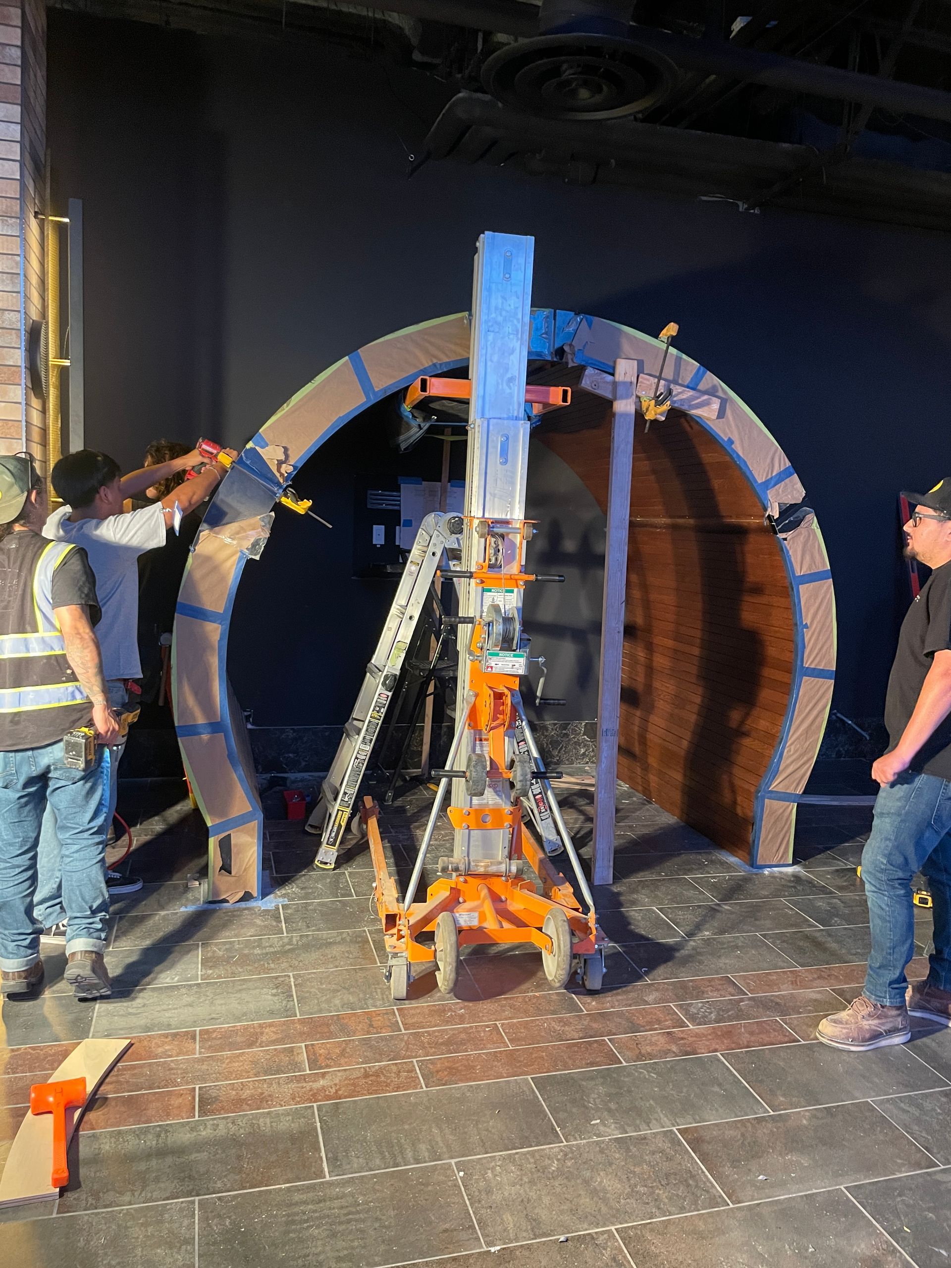 Two men inspecting a large circular industrial structure with a robotic rig in the center