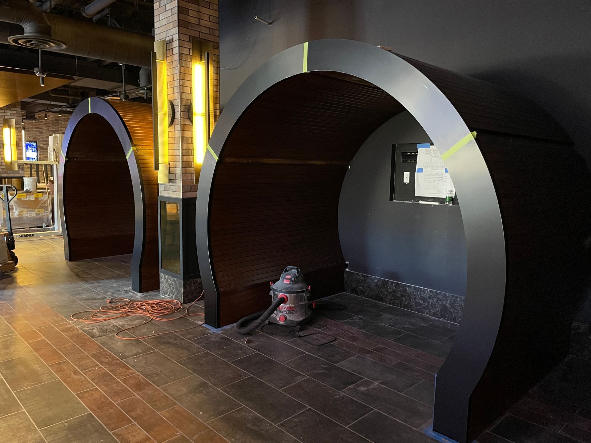 Urban street scene with black arched shelters and a wet tiled walkway at night