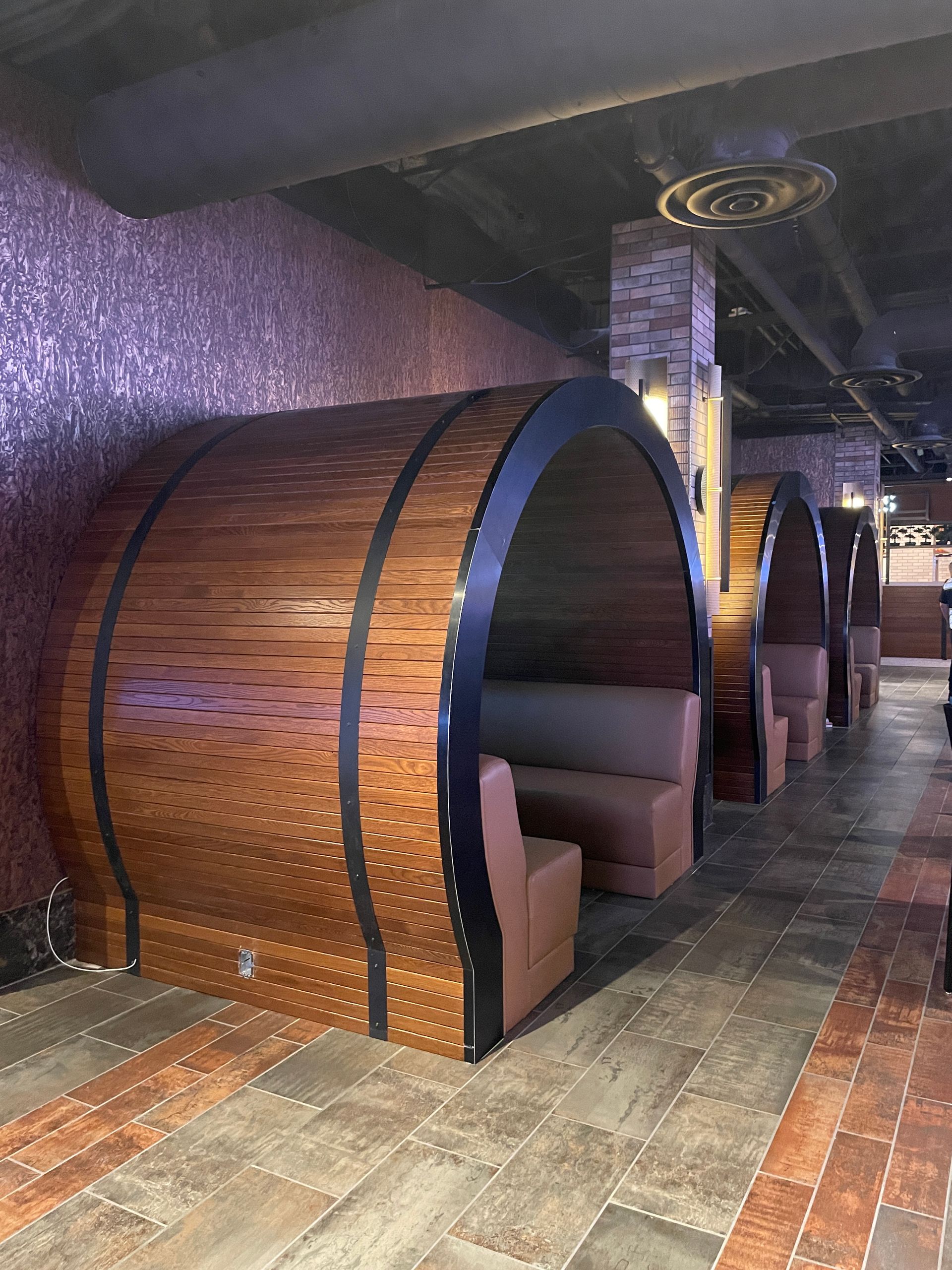 Wooden booth seats in a dimly lit restaurant with purple walls and patterned tile flooring.