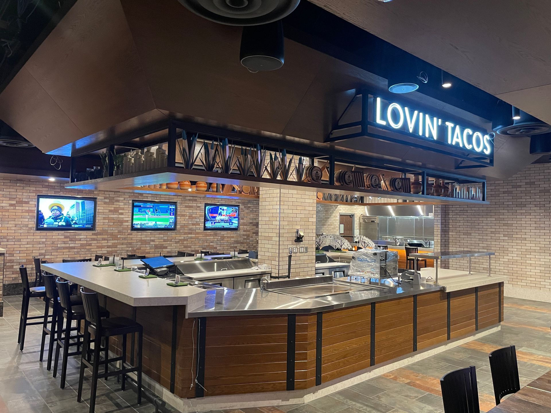 Lovin’ Tacos restaurant counter with TVs, wood paneling, and a stainless-steel service area