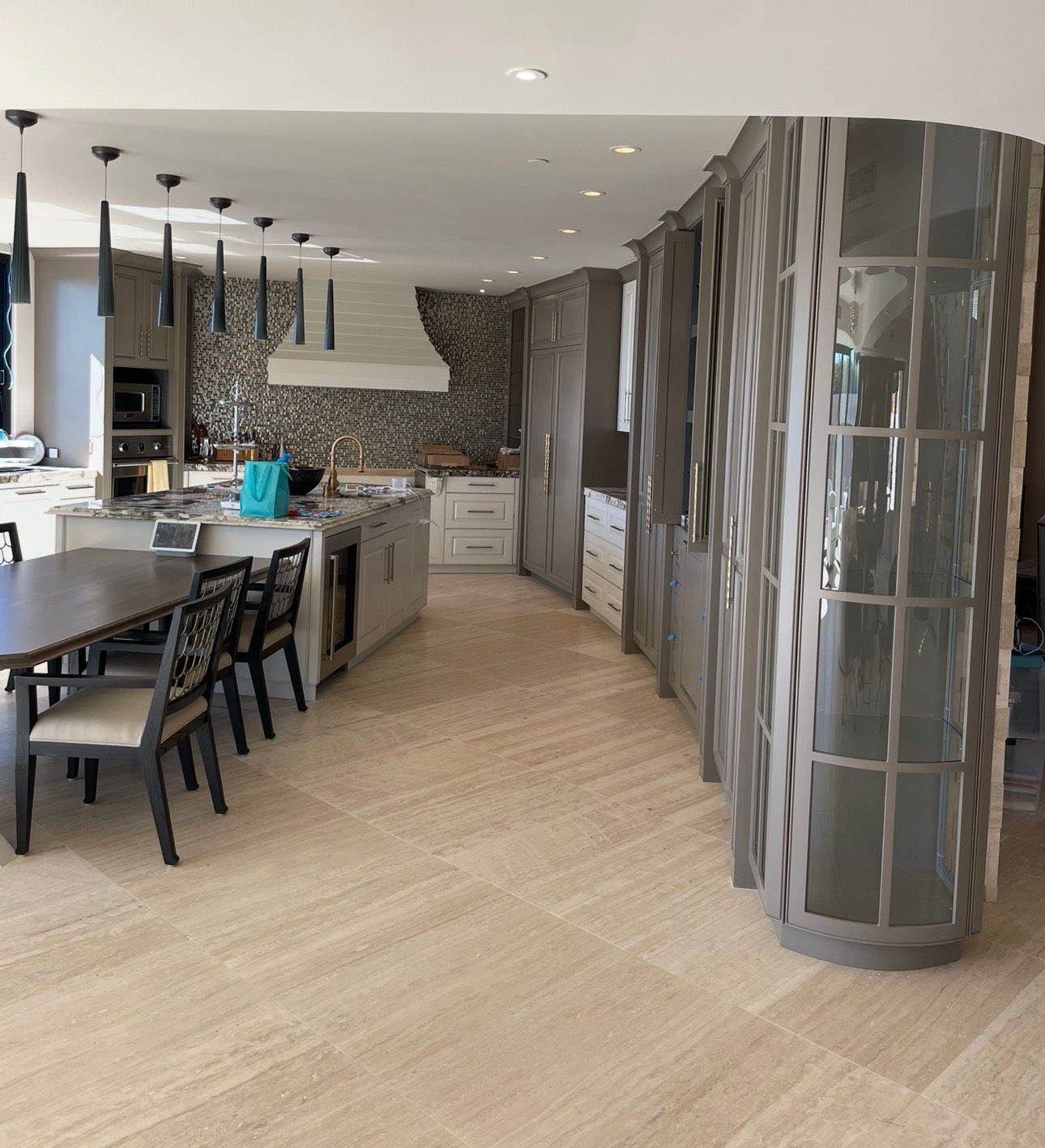 Modern kitchen and dining area with patterned walls, light flooring, and a large island with black chairs