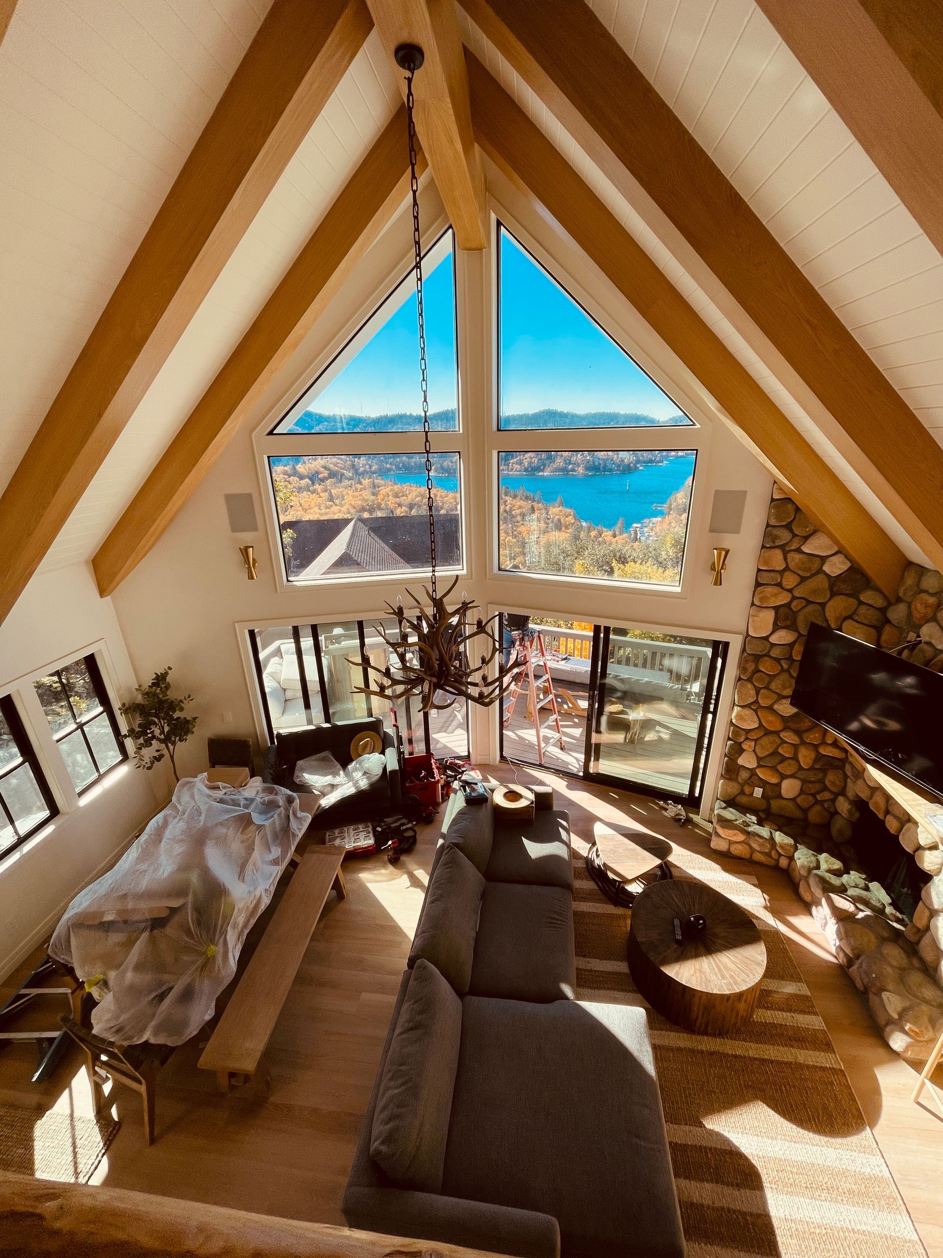 Cozy A-frame living room with large windows overlooking mountains and a blue lake