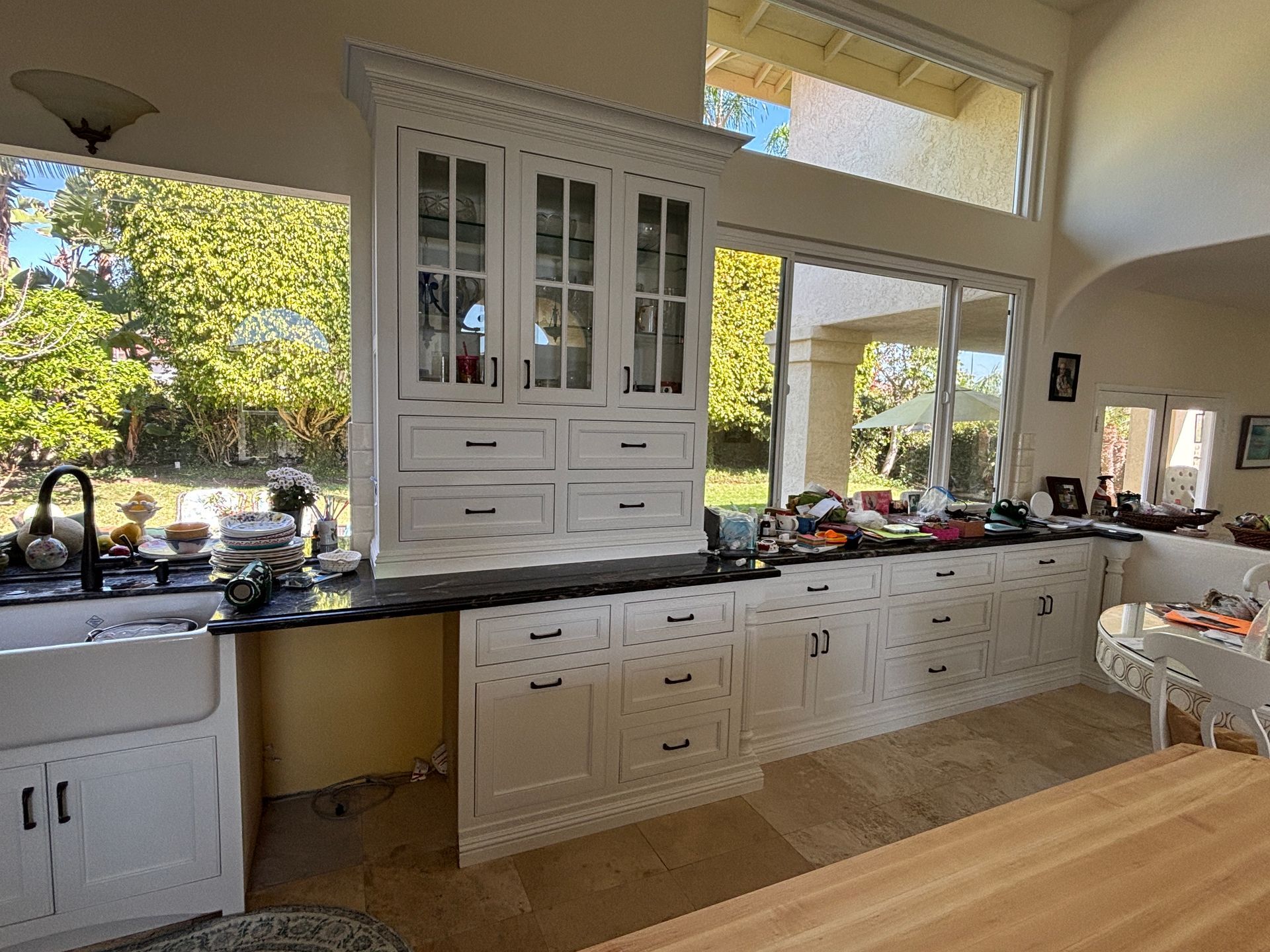 Bright kitchen with white cabinets, black countertops, and a large window above the sink.