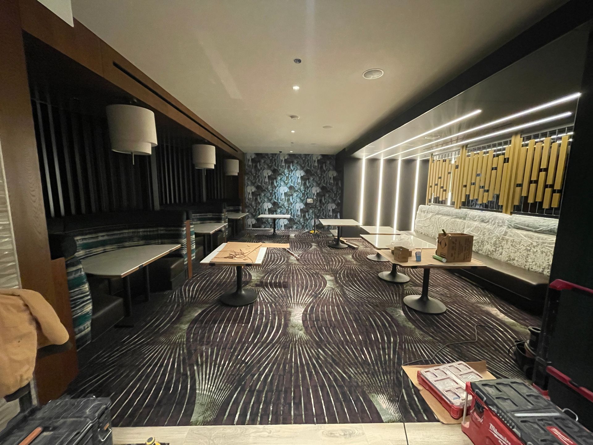 Modern lounge with patterned carpet, low tables, couches, and warm wall lighting in a sleek interior