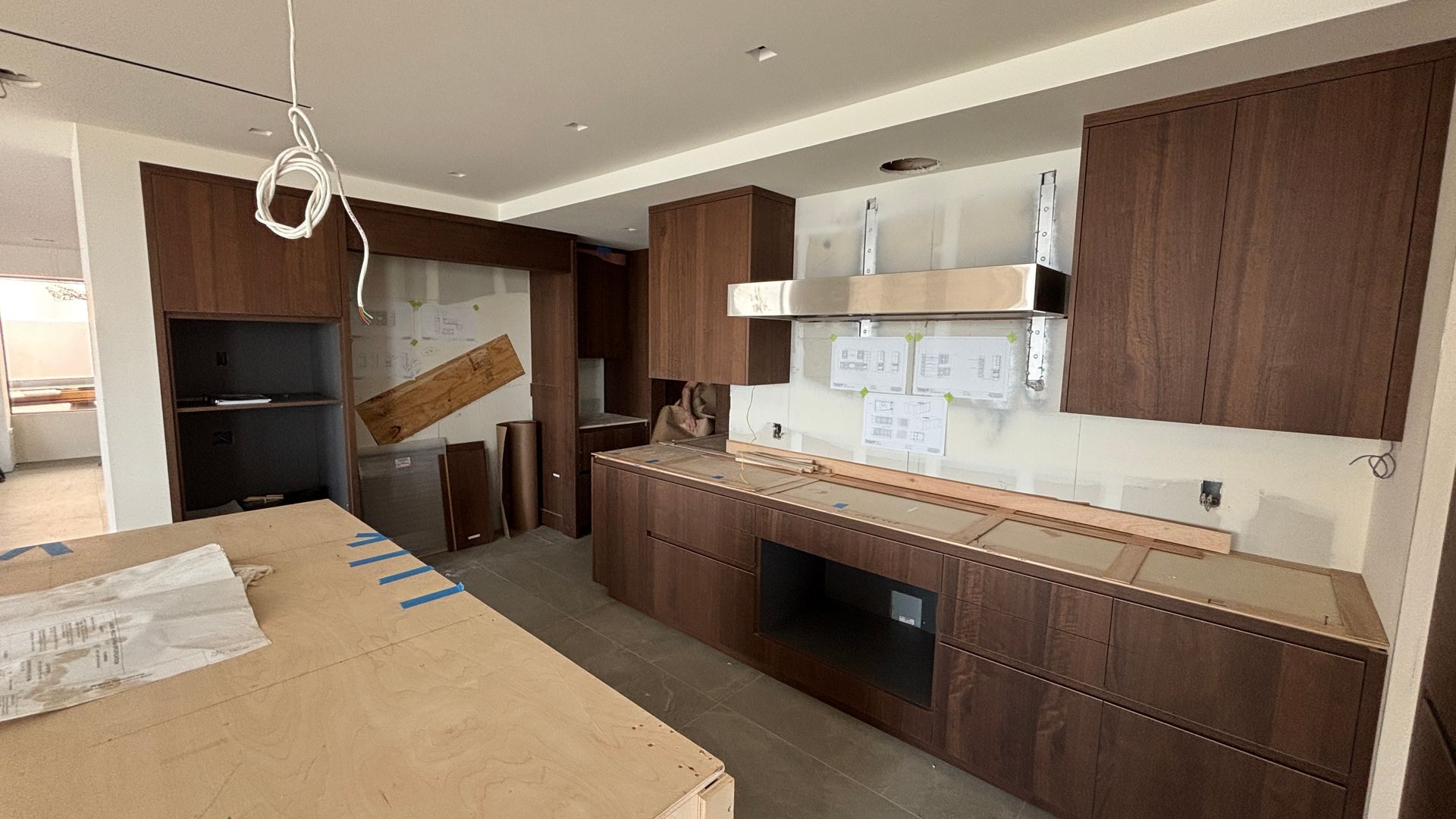 Modern kitchen with dark wood cabinets, white countertops, and an unfinished island under construction