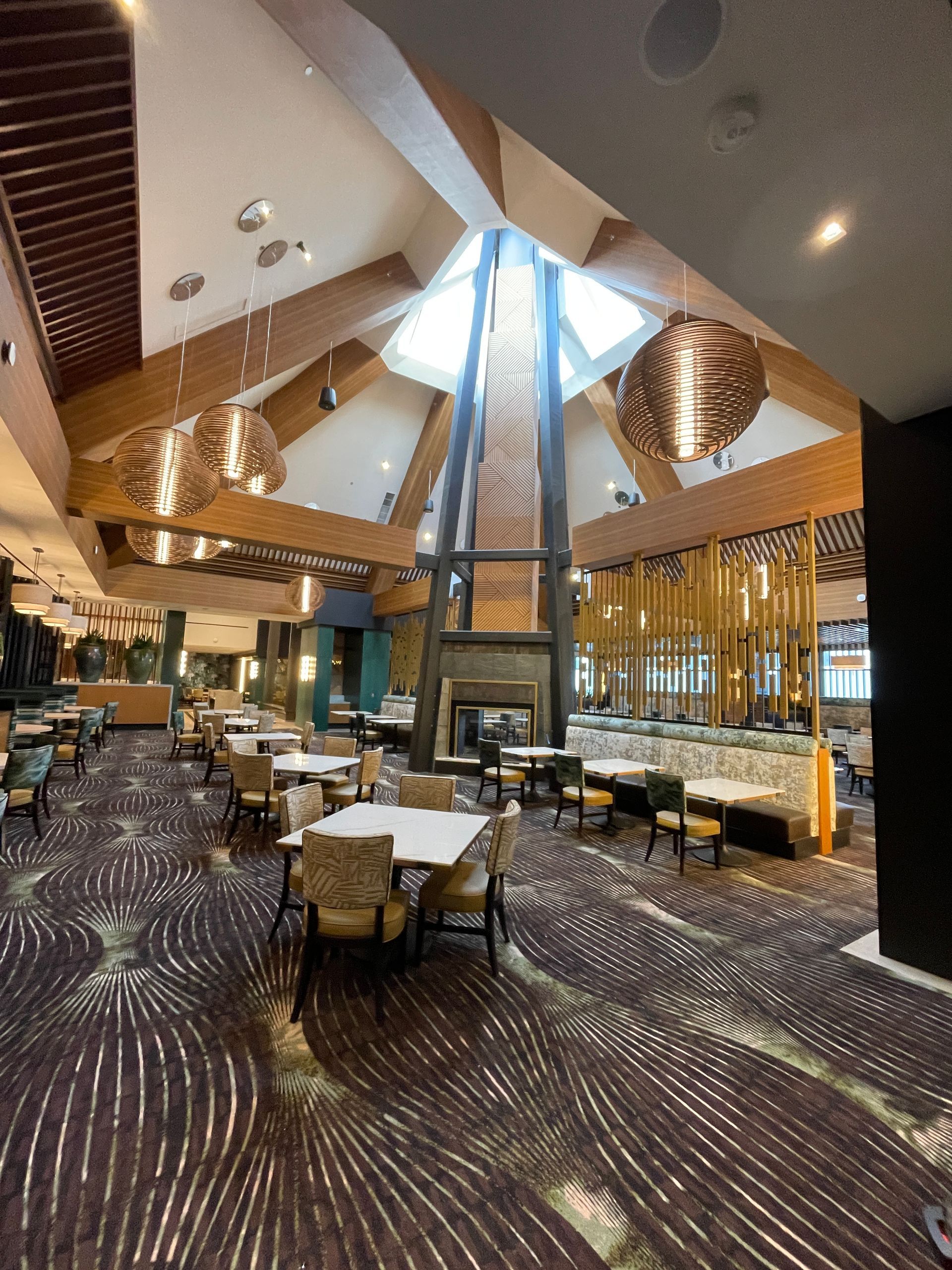 Elegant hotel restaurant with high vaulted ceiling, warm wood accents, and neatly set tables.