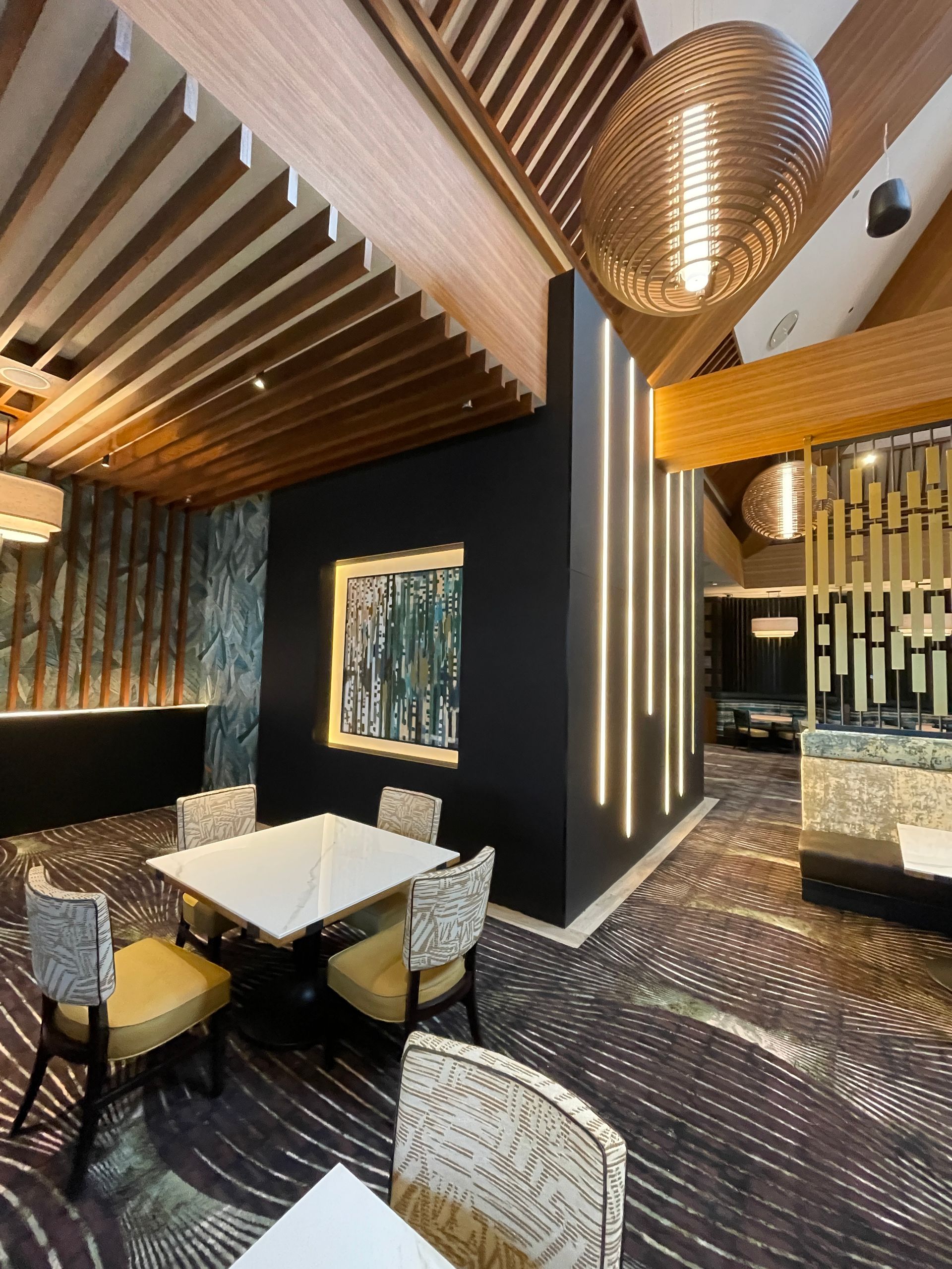 Stylish modern dining room with dark walls, patterned chairs, and a sculptural pendant light