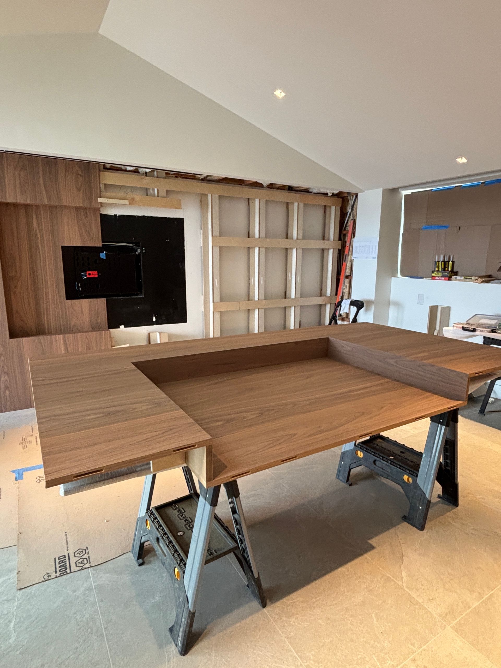 Wood-paneled dining room with a large table on sawhorses under renovation.