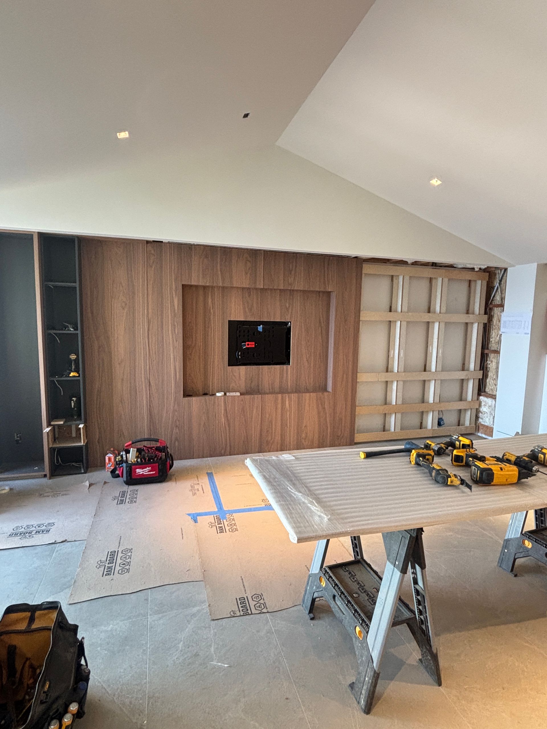 Renovation room with wood accent wall, ladder, tools, and toy trucks on a drop cloth floor