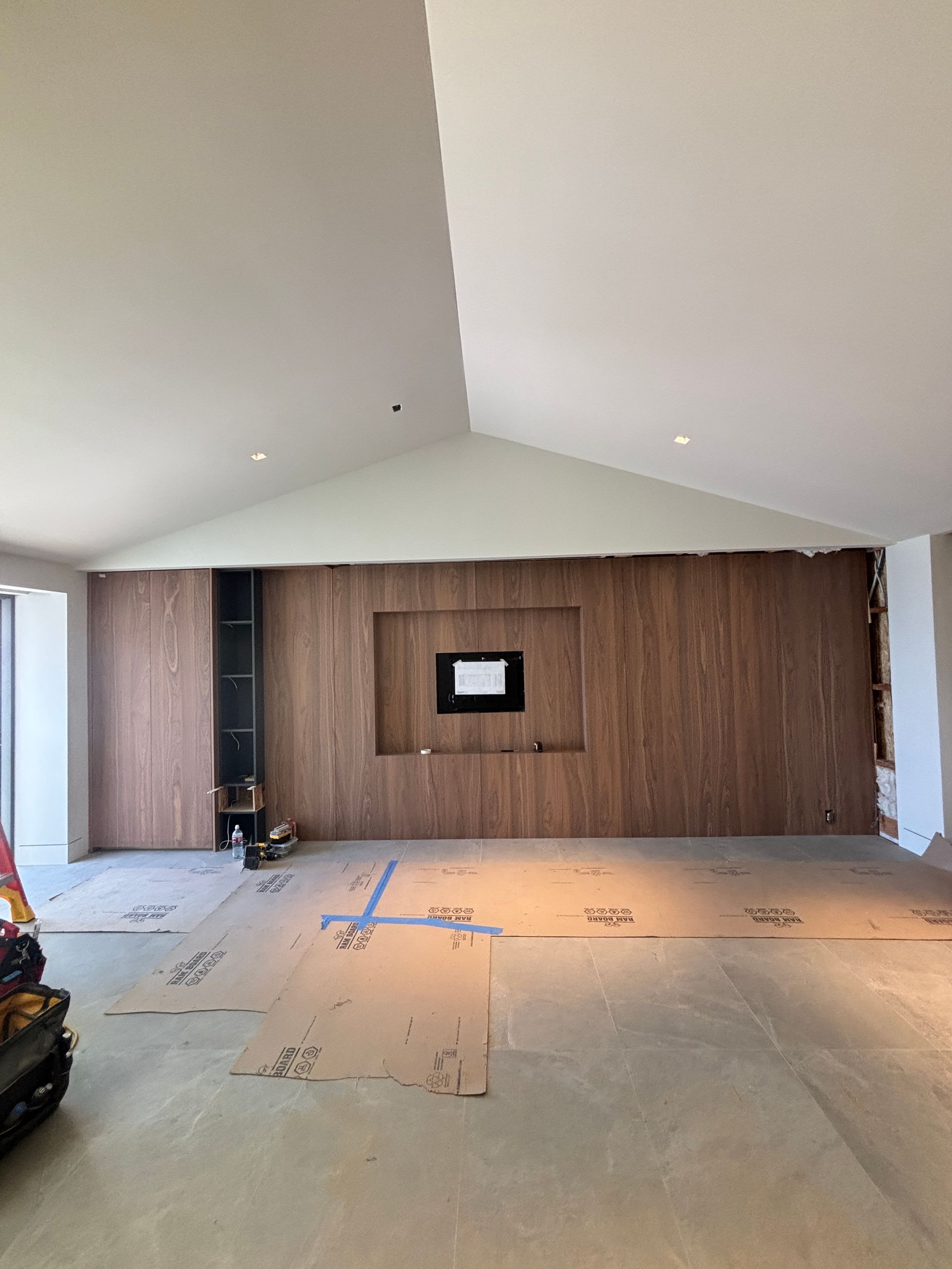 Renovated room with vaulted ceiling, wood accent wall, and construction materials on the floor